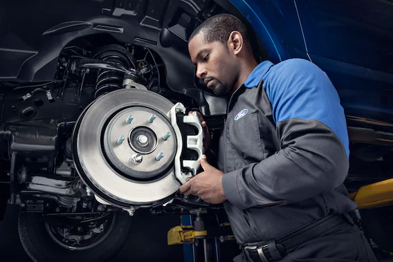 Professional Ford technician replacing brakes on a new Ford vehicle.