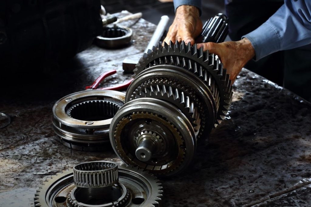 Close up shot of a mechanic tinkering with the inside pieces of a transmission on a work table. 