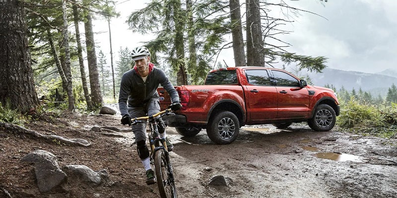 Handsome man took his brand new red 2023 Ford Ranger out on some mountainous trails to go biking.